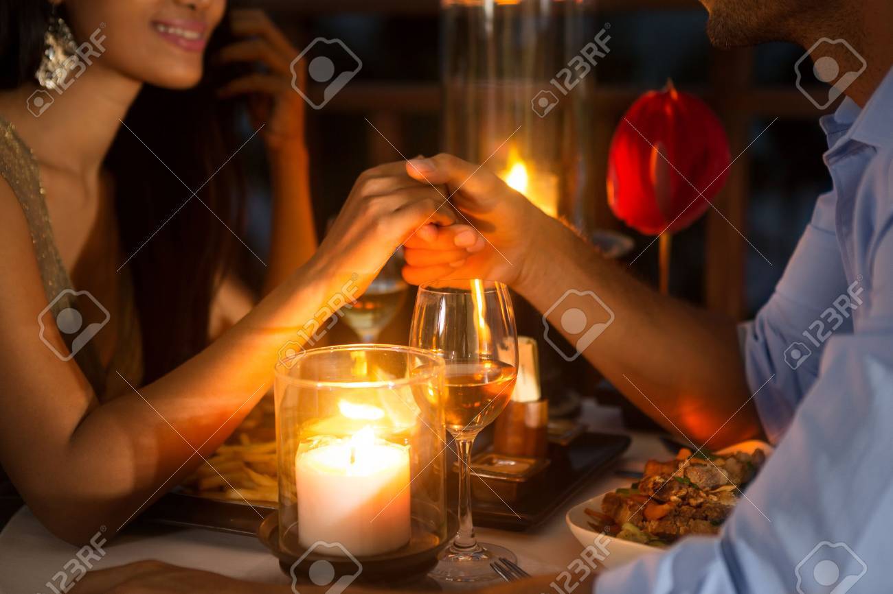 51516530_romantic_couple_holding_hands_together_over_candlelight_during_romantic_dinner.jpg