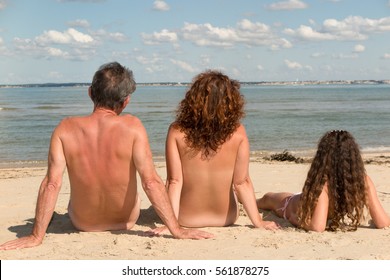 naked_family_sitting_on_beach_260nw_561878275.jpg