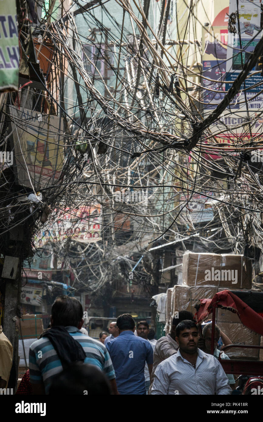 pedestrians_walking_in_narrow_street_with_large_tangled_birds_nest_of_power_cables_overhead_in_old_delhi_new_delhi_delhi_india_PK418R.jpg