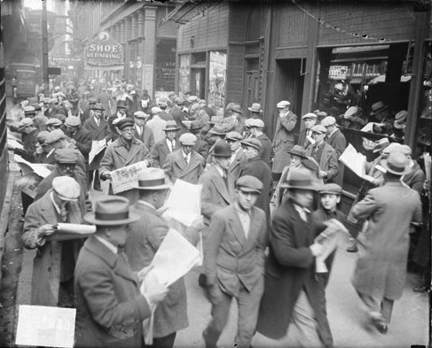 11.Crowd_of_unemployed_men_reading_newspapers__standing_on_the_sidewalk_in_front_of_the_Chicago_Daily_News_building__boy_in_the_foreground.jpg