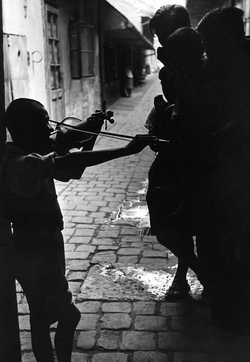 A_young_boy_playing_his_violin_for_his_play_mates_in_the_slums_where_the_gypsies_live__Hungary__1937.jpg
